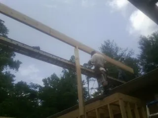 Carpenter setting a ridge beam over a new addition frame — Ice Dam Removal by Roofing Brothers in Gassaway