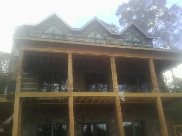 Dormers and porch framing on a large log home under construction — Roof Coating work by our crew in Gassaway