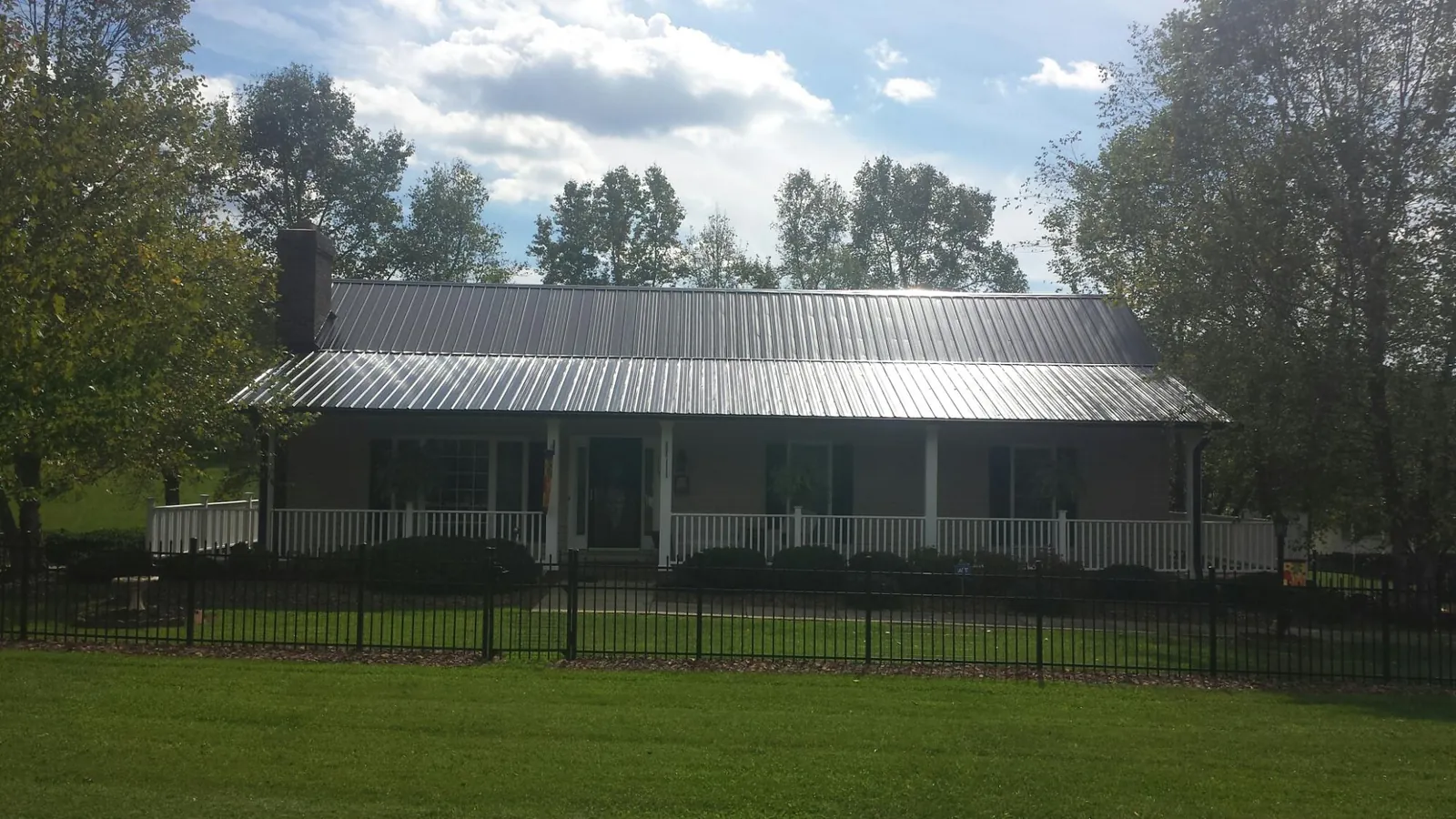 Gray metal roof on a brick ranch with a full width front porch — Gutter Guard Installation work by our crew in Gassaway