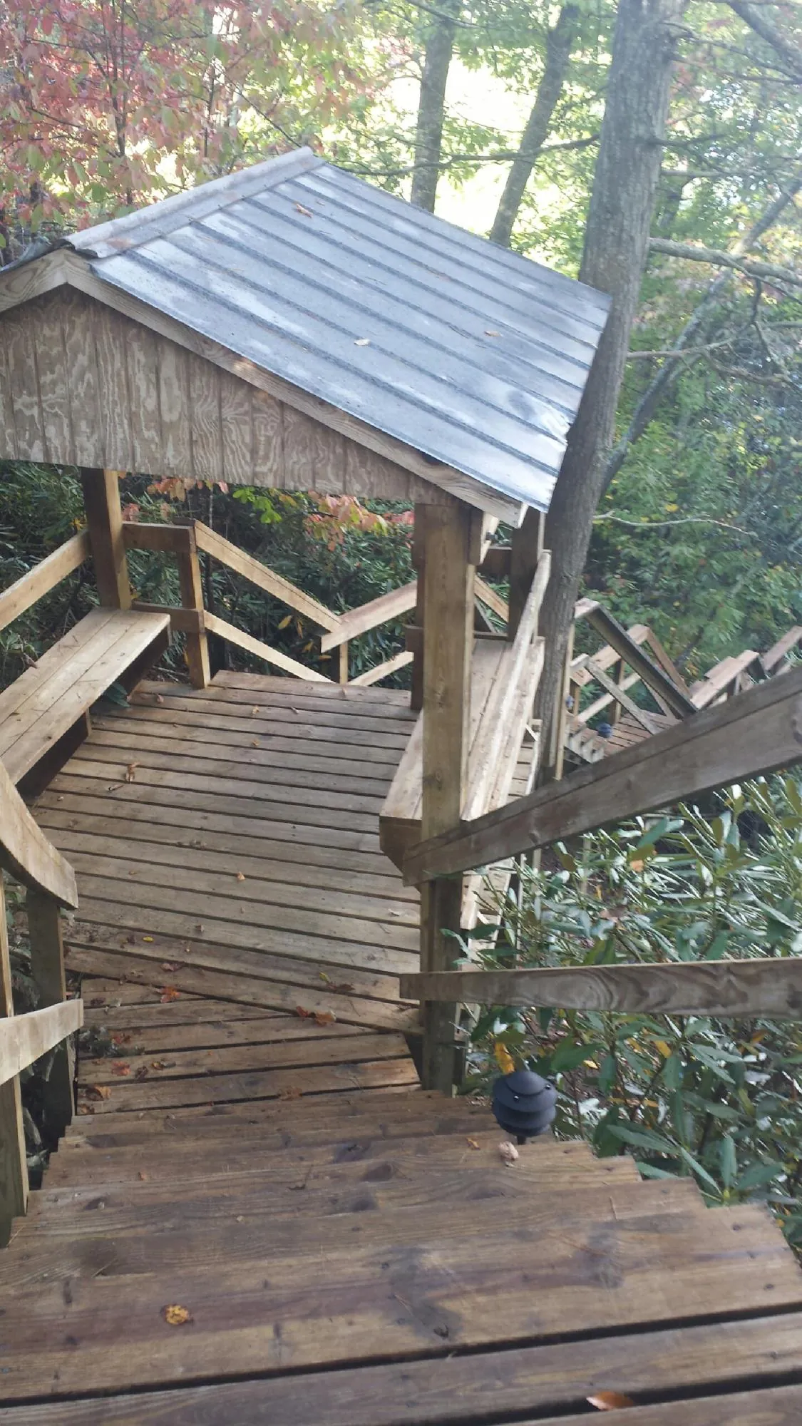 Metal roofed shelter over wooden steps on a wooded walkway — Skylight Repair & Installation work by our crew in Gassaway