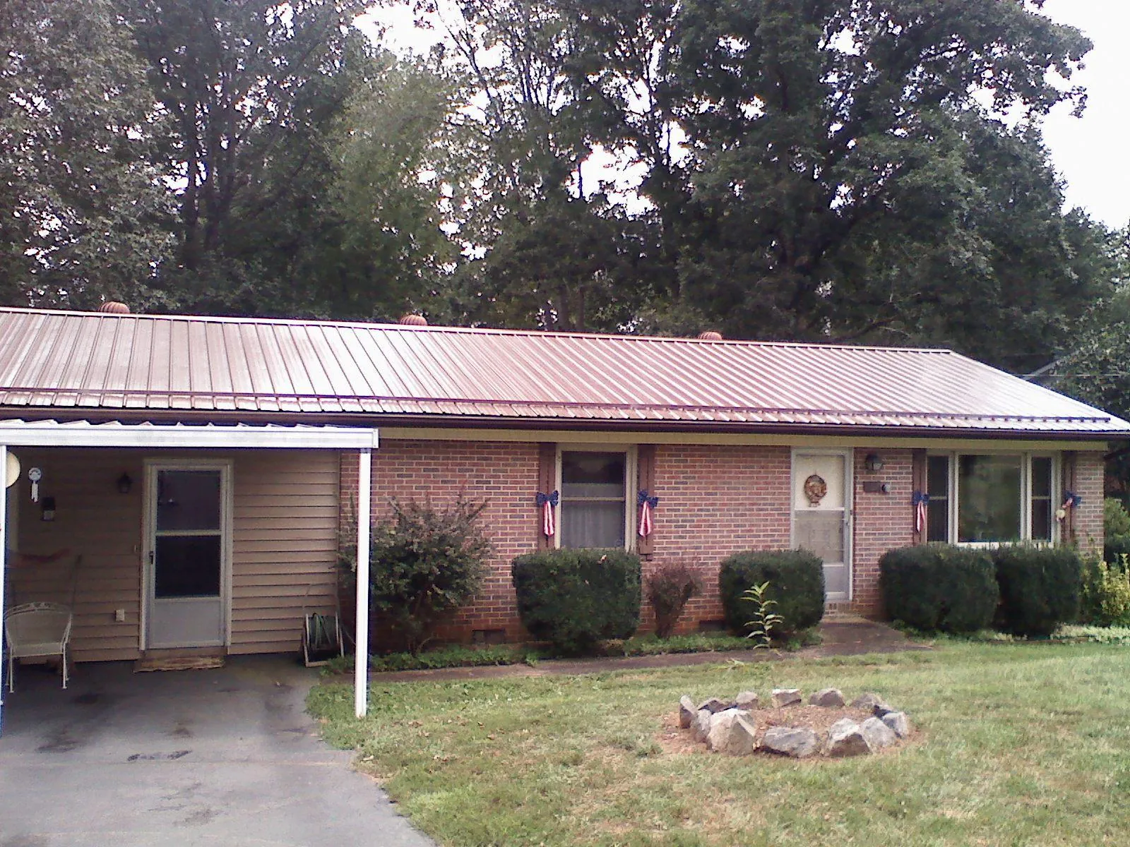 Bronze metal roof and carport on a brick ranch home — Roof Repair work by our crew in Gassaway