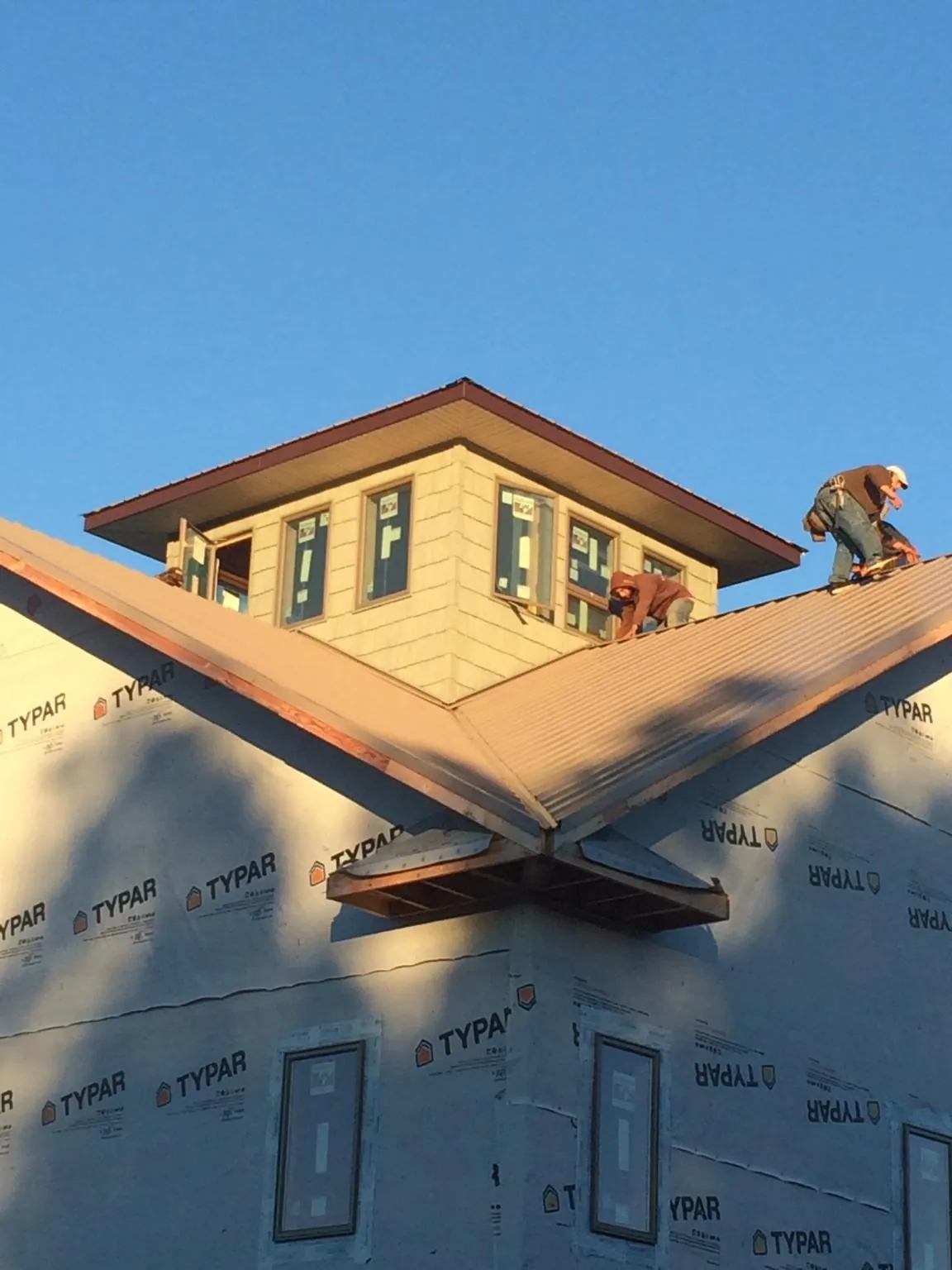 Roofers working around a rooftop cupola on a new metal roof at sunset — Roof Waterproofing in Gassaway by Roofing Brothers